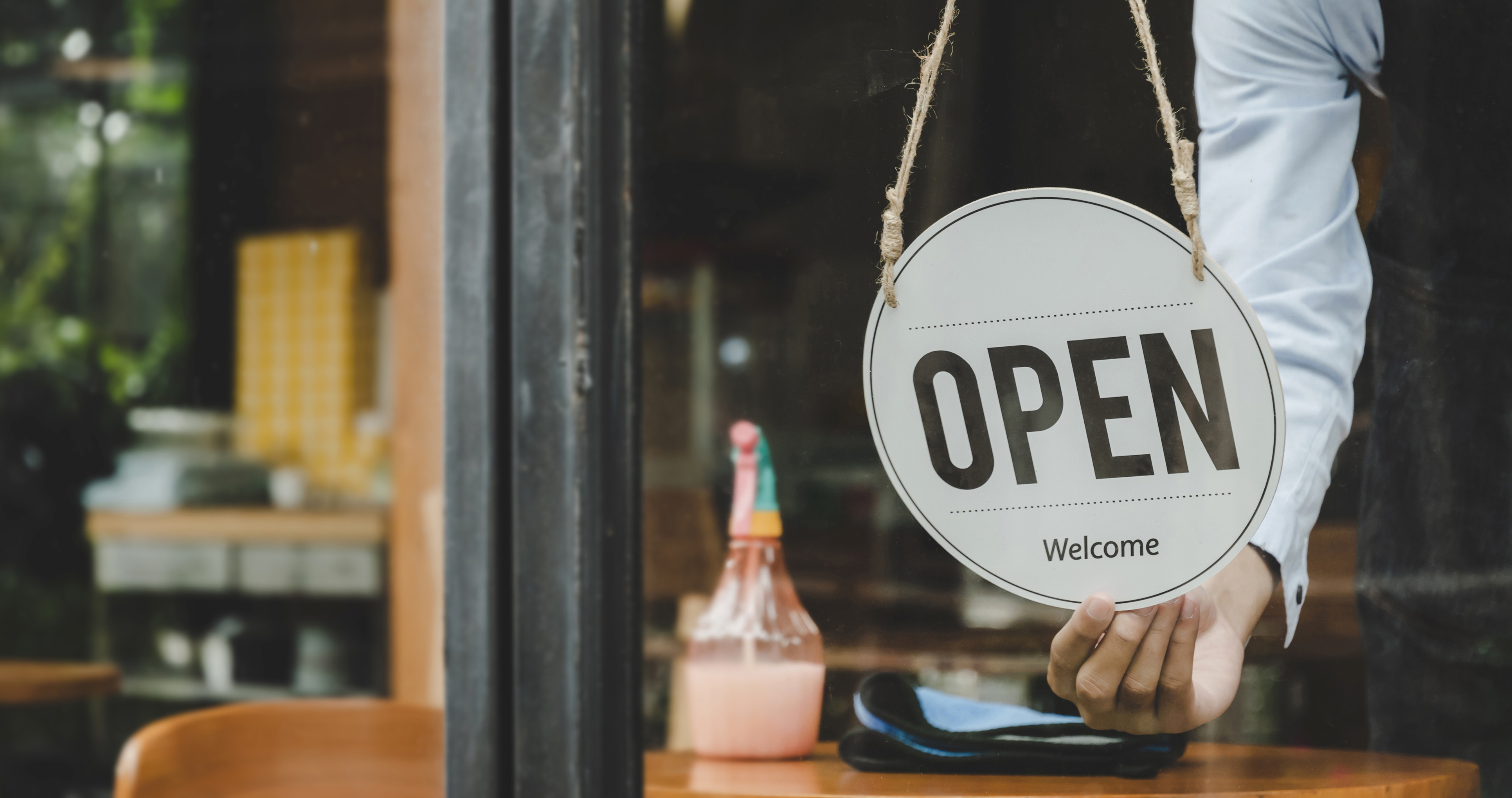 Shop owner turning a sign to Open