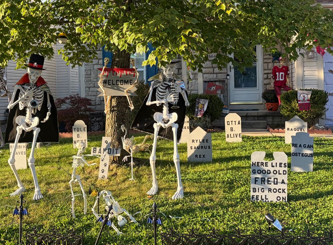 Front-yard graveyard: caped skeletons playing trumpet and clarinet among tombstones reading Yule B. Next, Otta B. Alive and Rylee Saurus Rex, under a Welcome sign