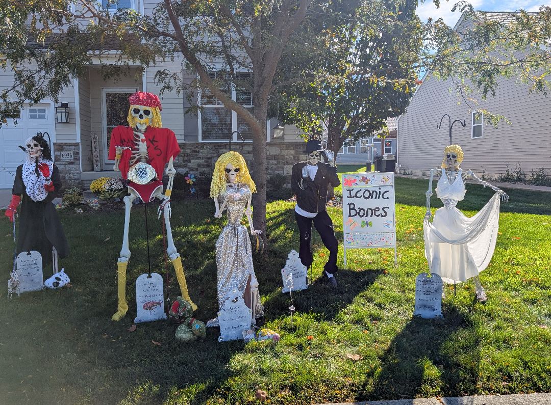 Iconic Bones display: skeletons dressed as Cruella de Vil, Hulk Hogan, Dolly Parton, Michael Jackson and Marilyn Monroe, each with a tombstone, beside a hand-painted Iconic Bones sign